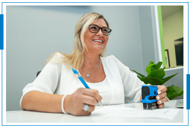 A woman sitting at a table with a pen in her hand.